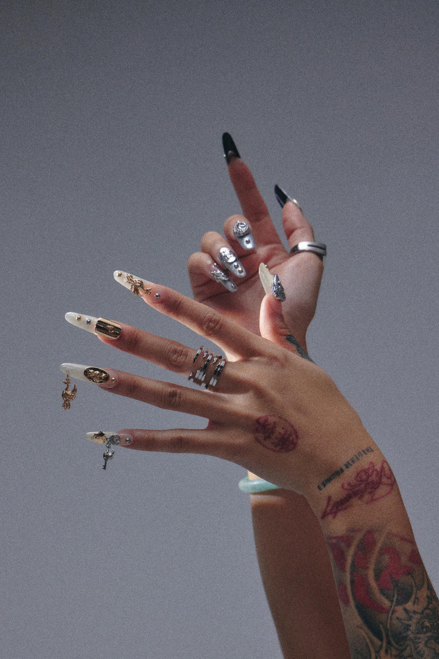 Hands wearing Coca Michelle Rising Collection nail charms